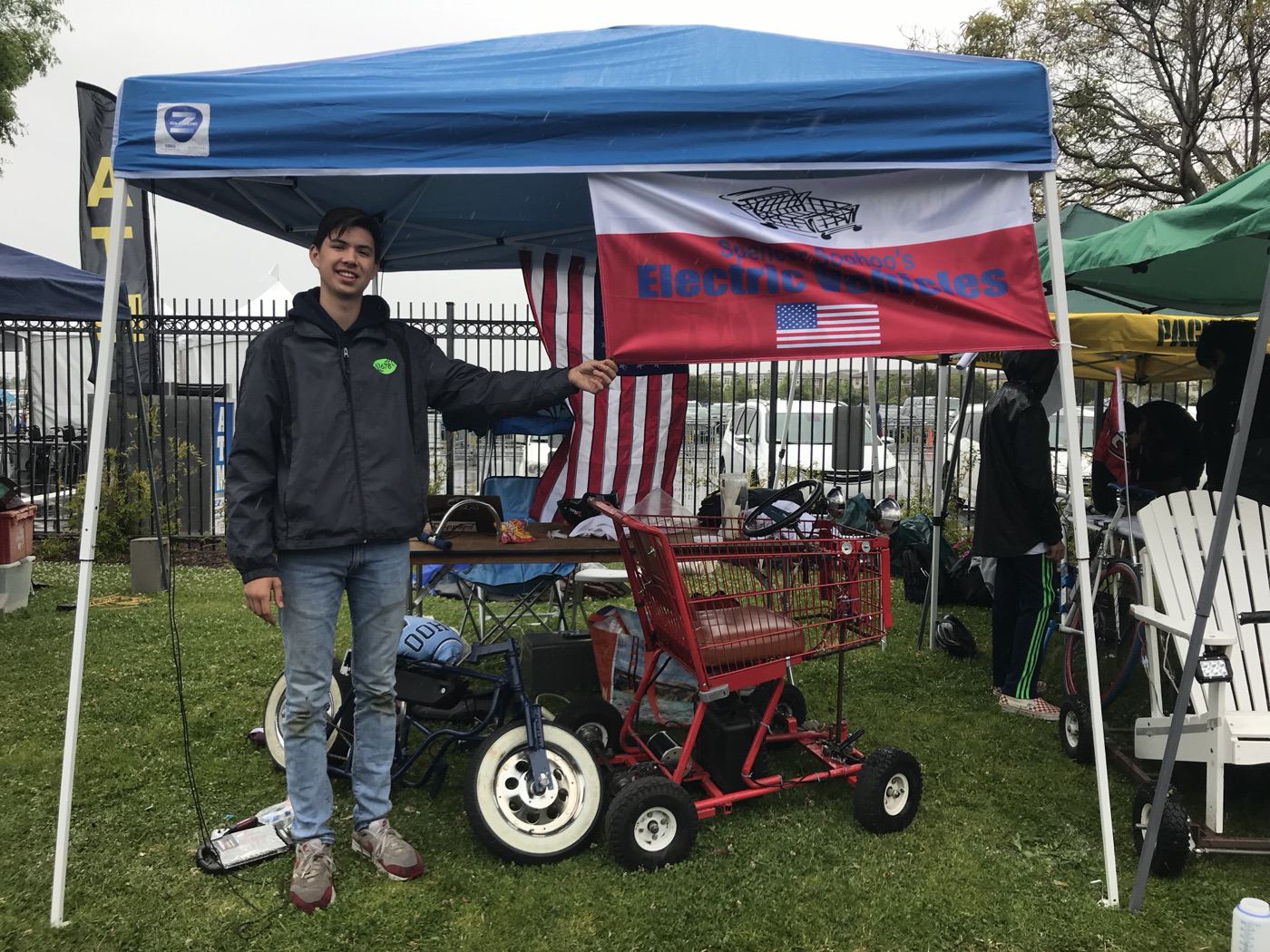 Spencer with the shopping-cart go-kart at a race event booth
