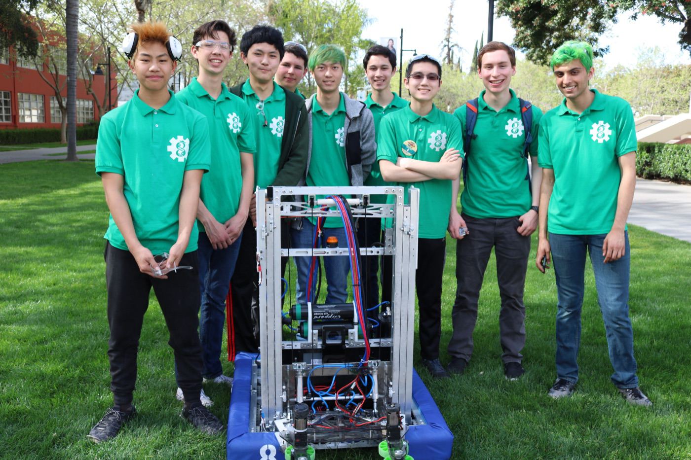 High school robotics team in green shirts posing with their competition robot