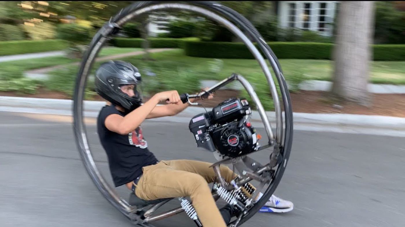 Spencer riding a scratch-built monowheel at speed down a neighborhood street