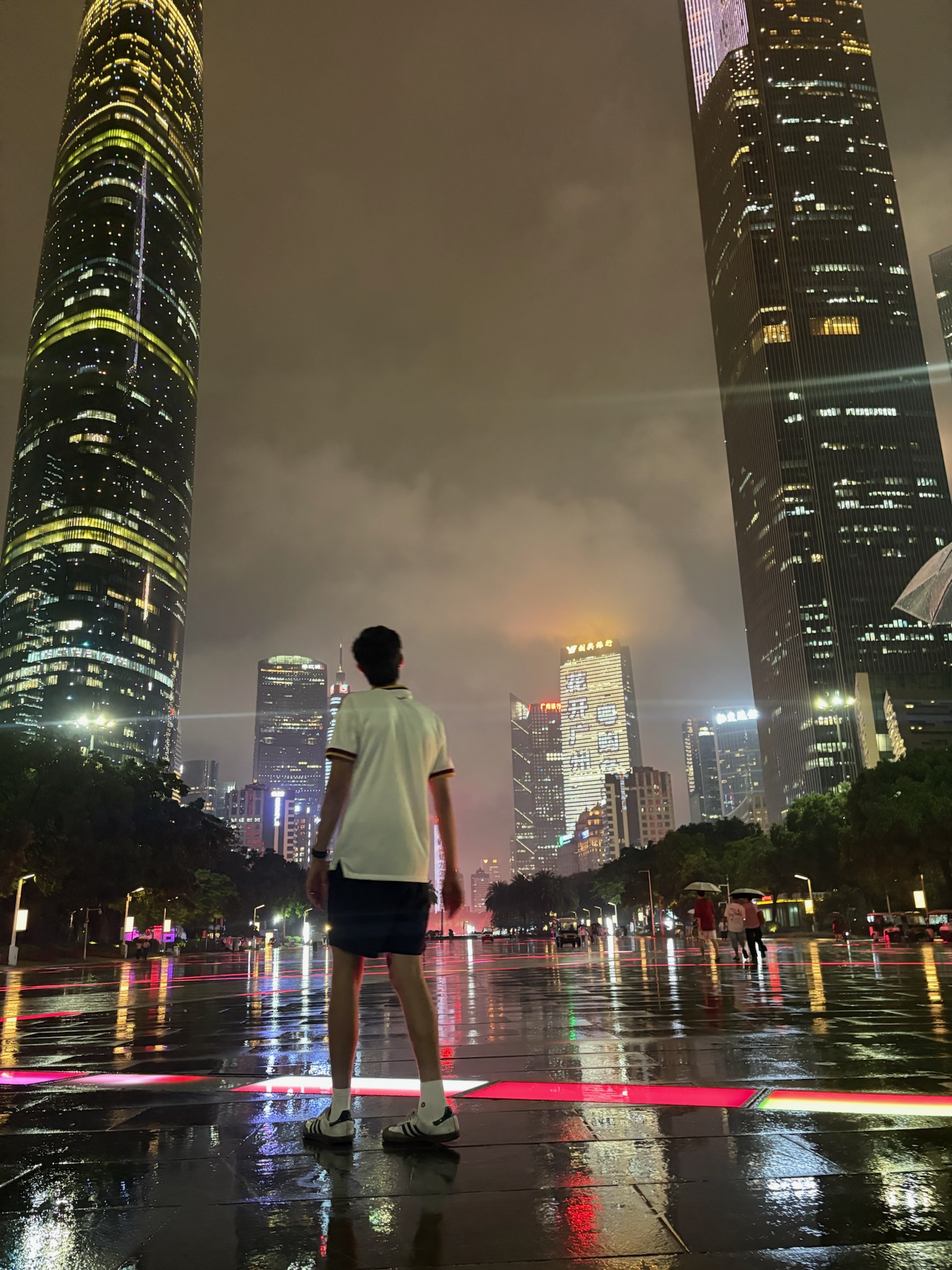 Spencer standing in the rain in front of the Guangzhou CBD skyline